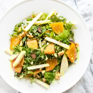 A roasted beet salad on a white plate, blue linen towel to the side