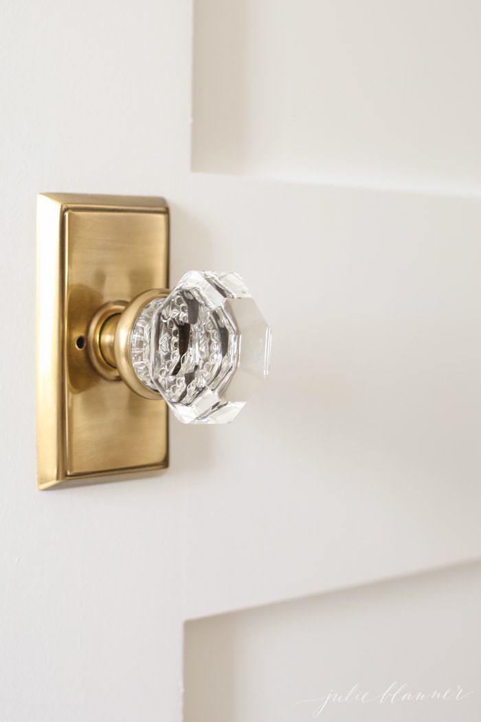 A white door with a brass switchplate and a glass knob.
