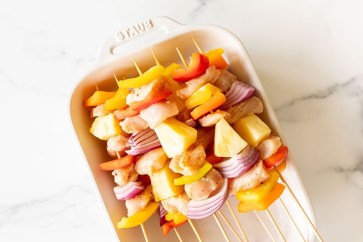 uncooked chicken kabobs in a white baking dish prior to grill