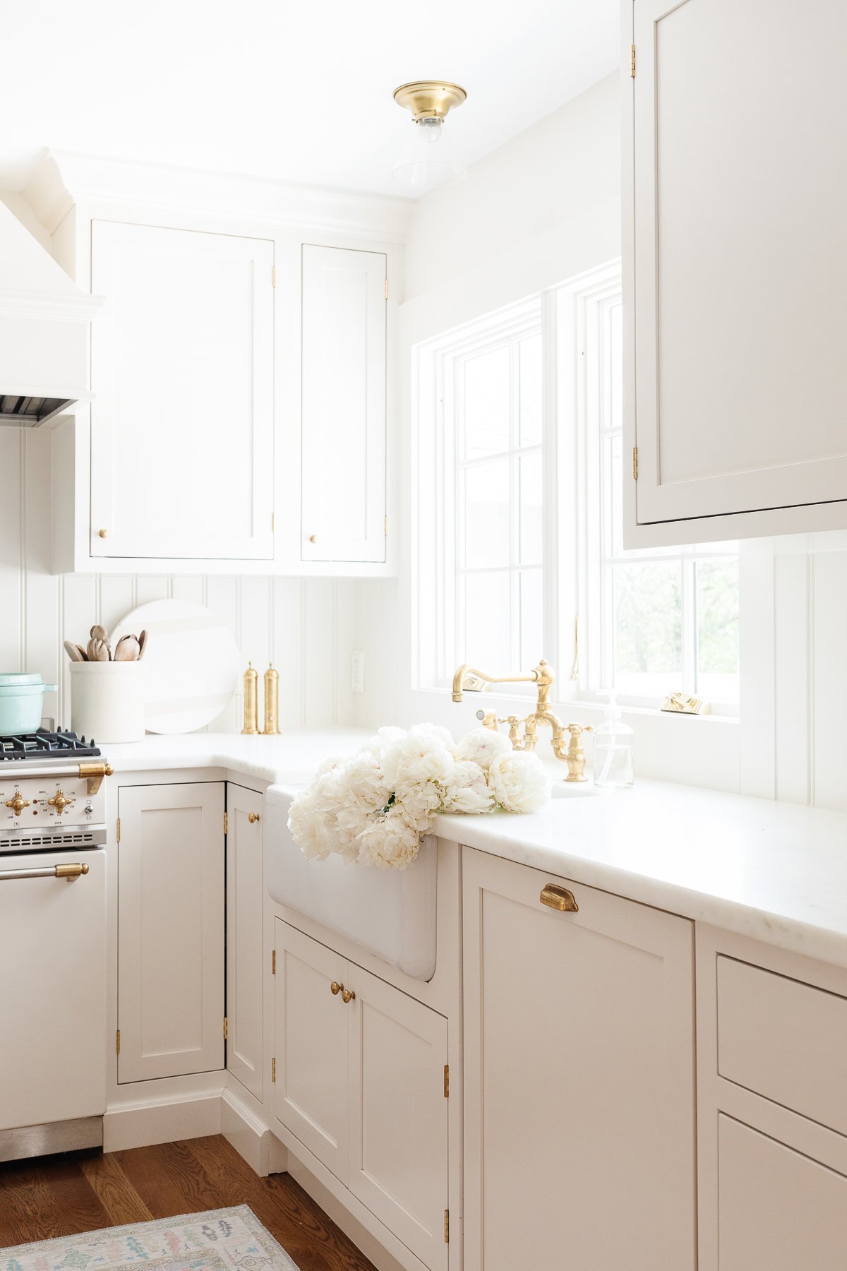 A cream kitchen with brass hardware, a farm sink and Danby marble countertops.