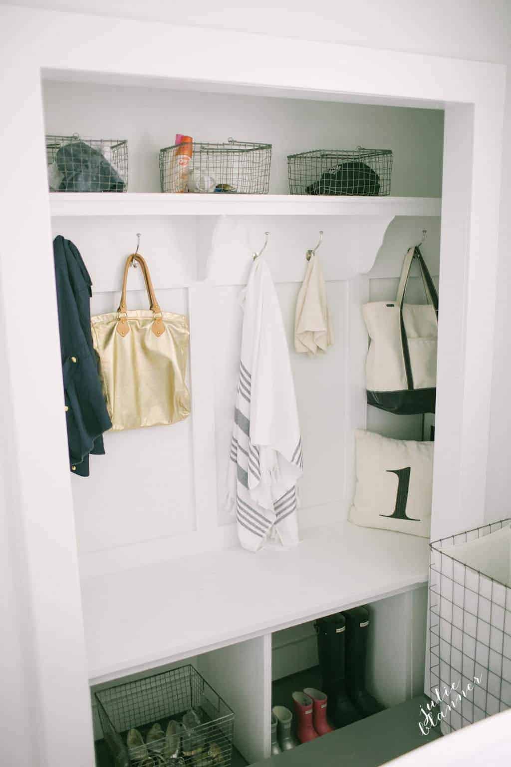 A closet mudroom with shelves, baskets, hooks and bemch.