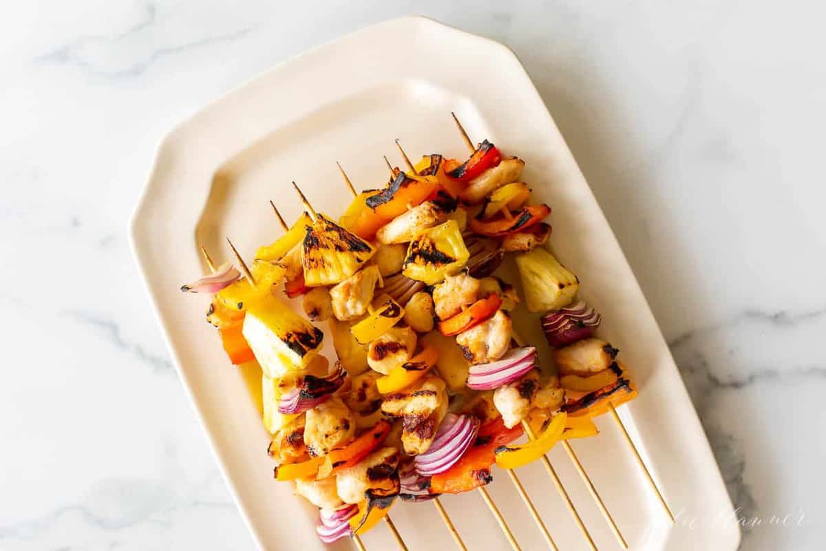 Colorful chicken kabobs on a cream platter. 