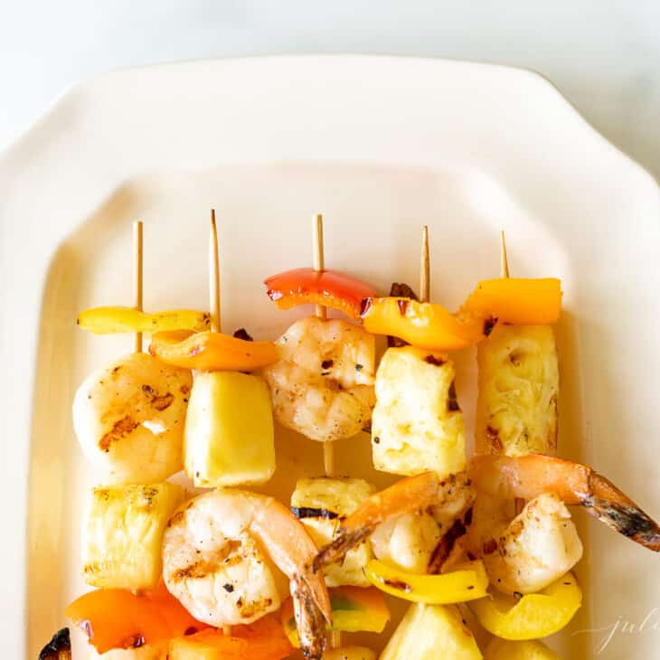 Pineapple shrimp skewers recipe on a white platter.