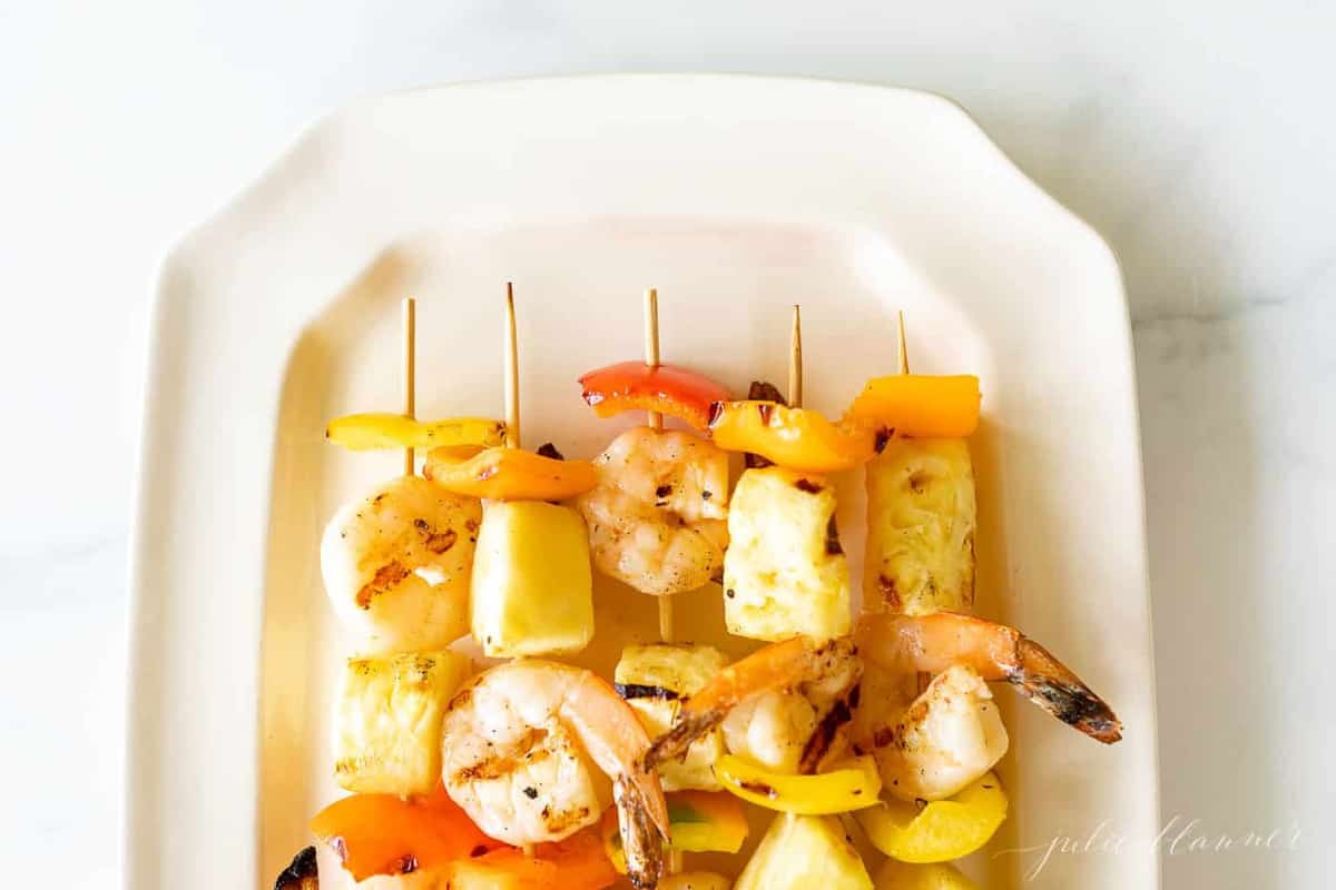 Pineapple shrimp skewers recipe on a white platter.
