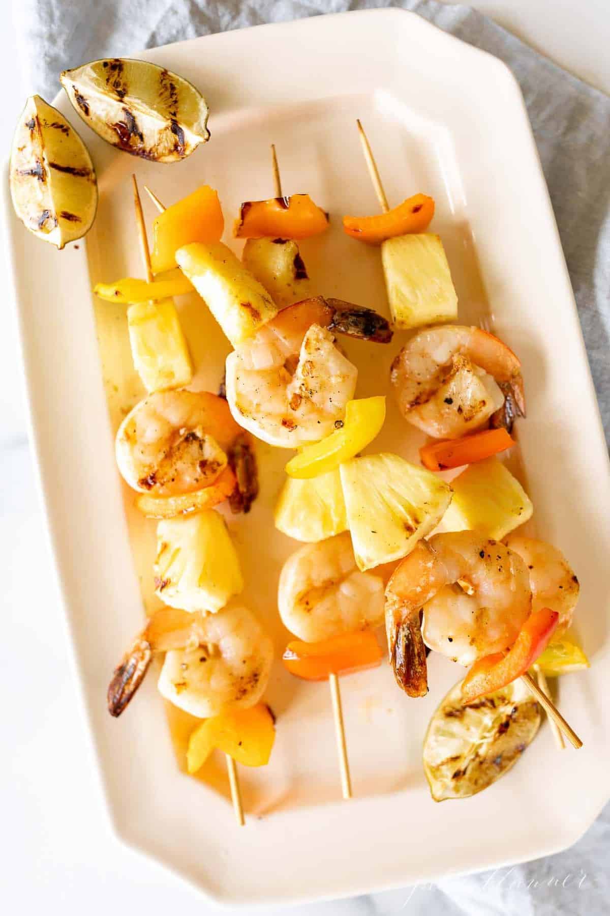 A white platter filled with pineapple shrimp skewers. 