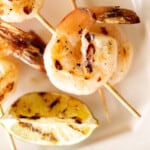 A white platter filled with grilled shrimp skewers.