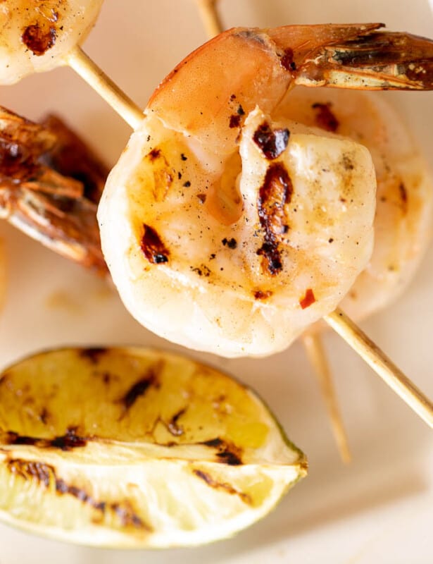 A white platter filled with grilled shrimp skewers.