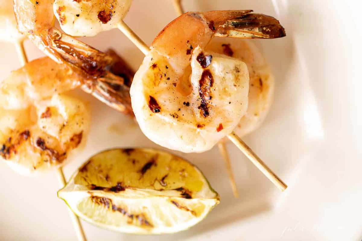 A white platter filled with grilled shrimp skewers.