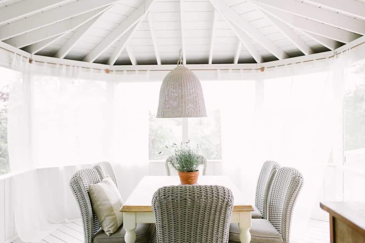 Wicker seating at a dining table on a screened in porch.
