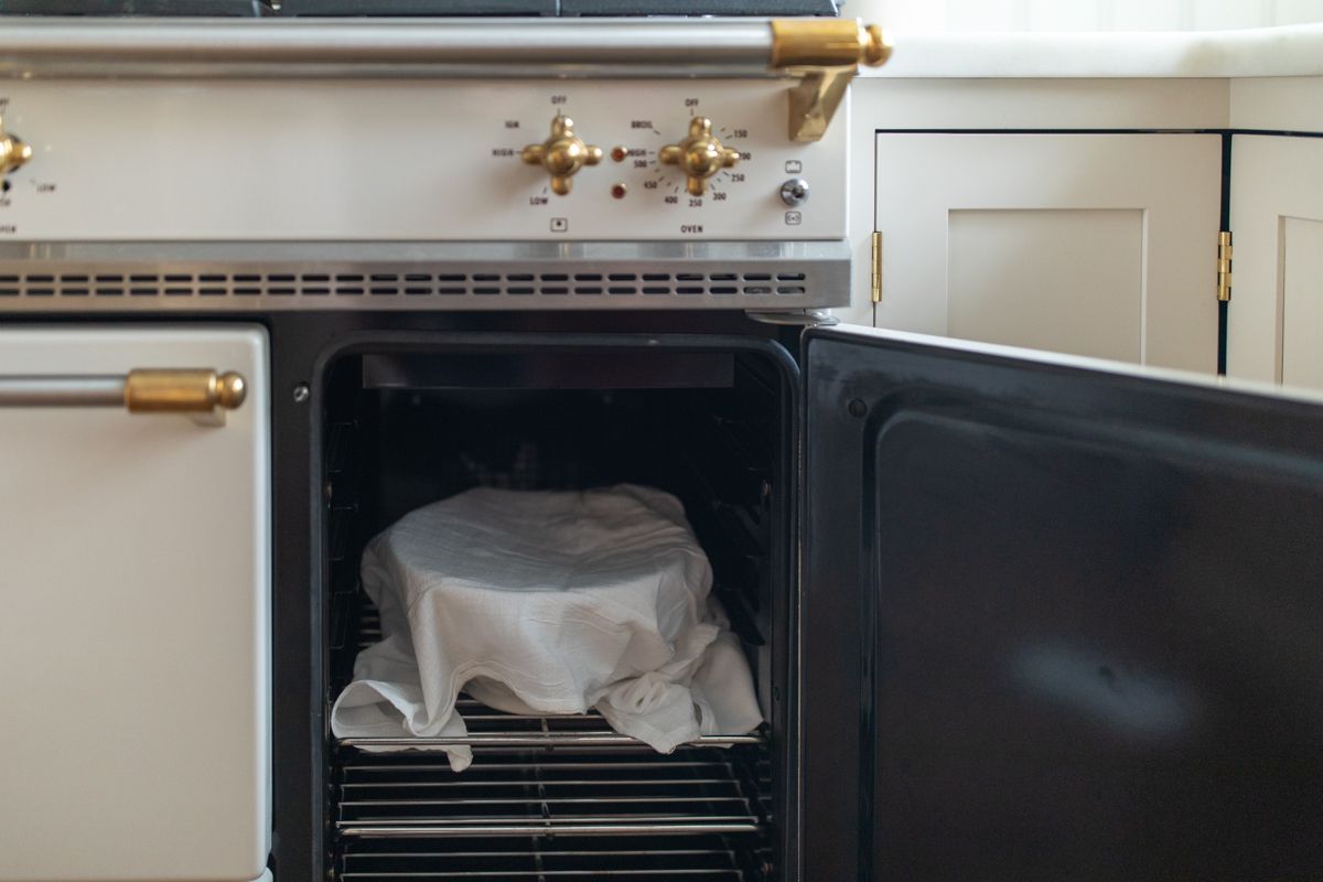 Looking inside an oven, with a bowl topped with a towel.