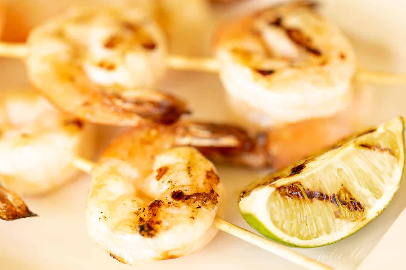Grilled shrimp skewers with a grilled slice of lime.