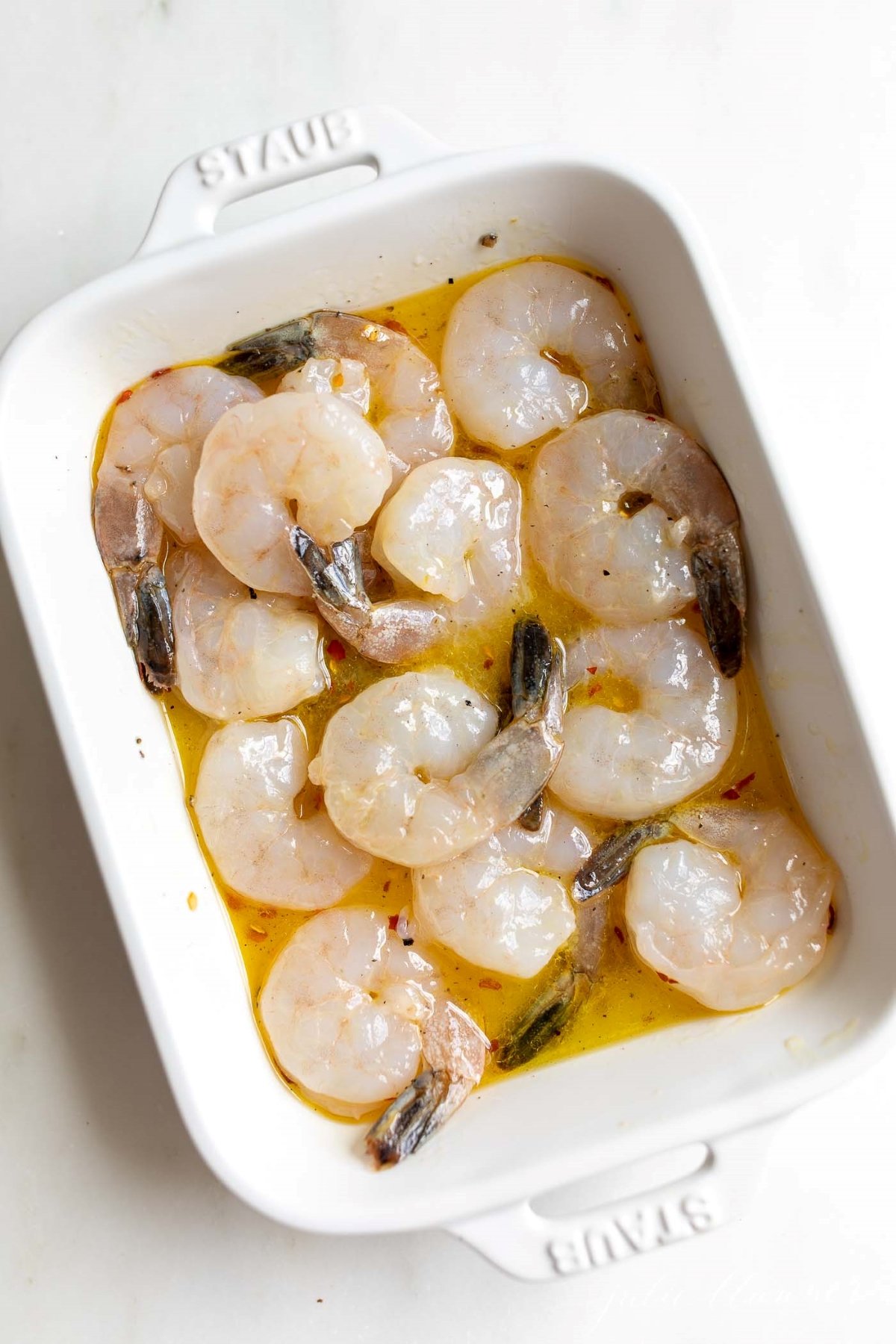 Tequila shrimp marinade with raw shrimp, in a white pan