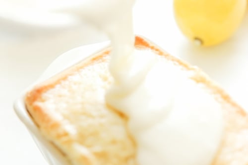 Pouring lemon glaze over a slice of lemon cake.
