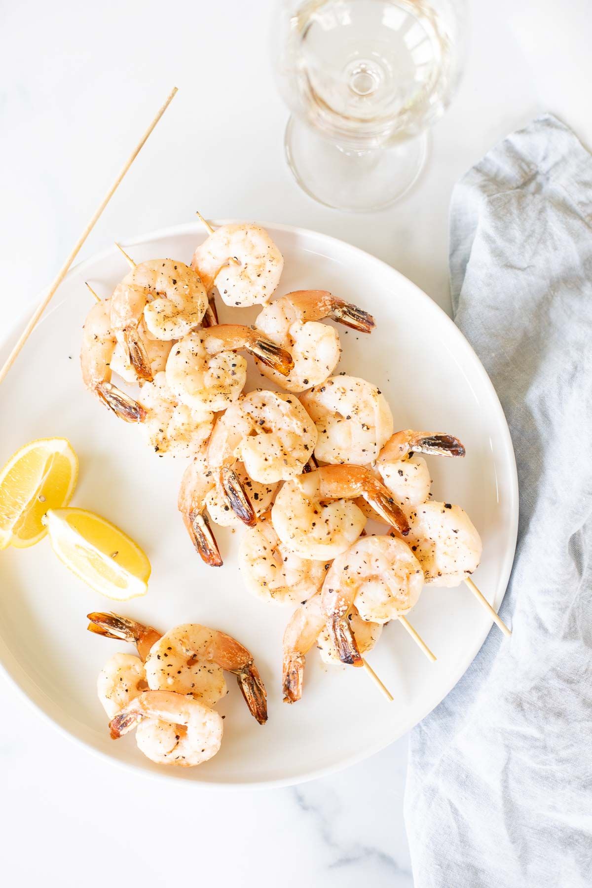 A white plate with lemon pepper shrimp kabobs