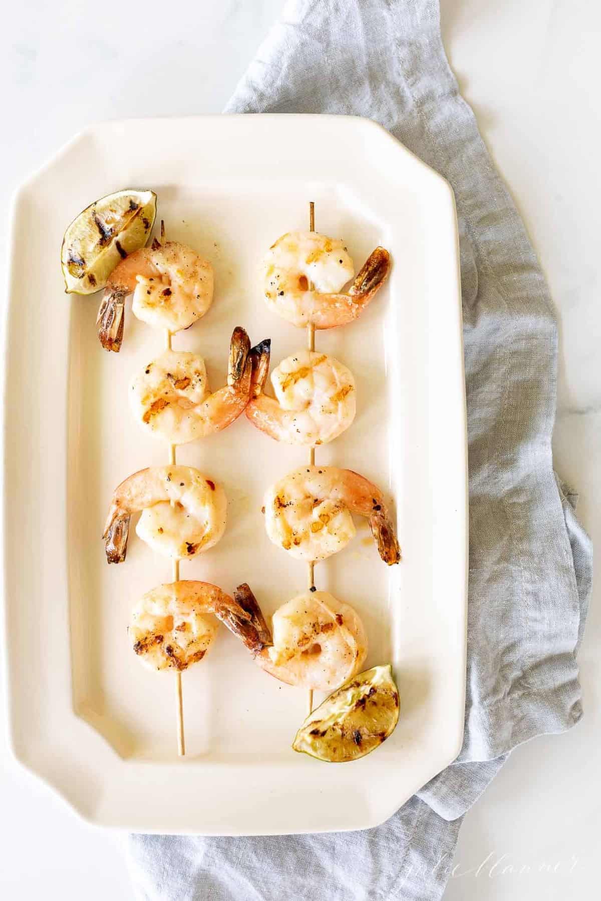 Zesty tequila lime shrimp skewers on a cream platter.