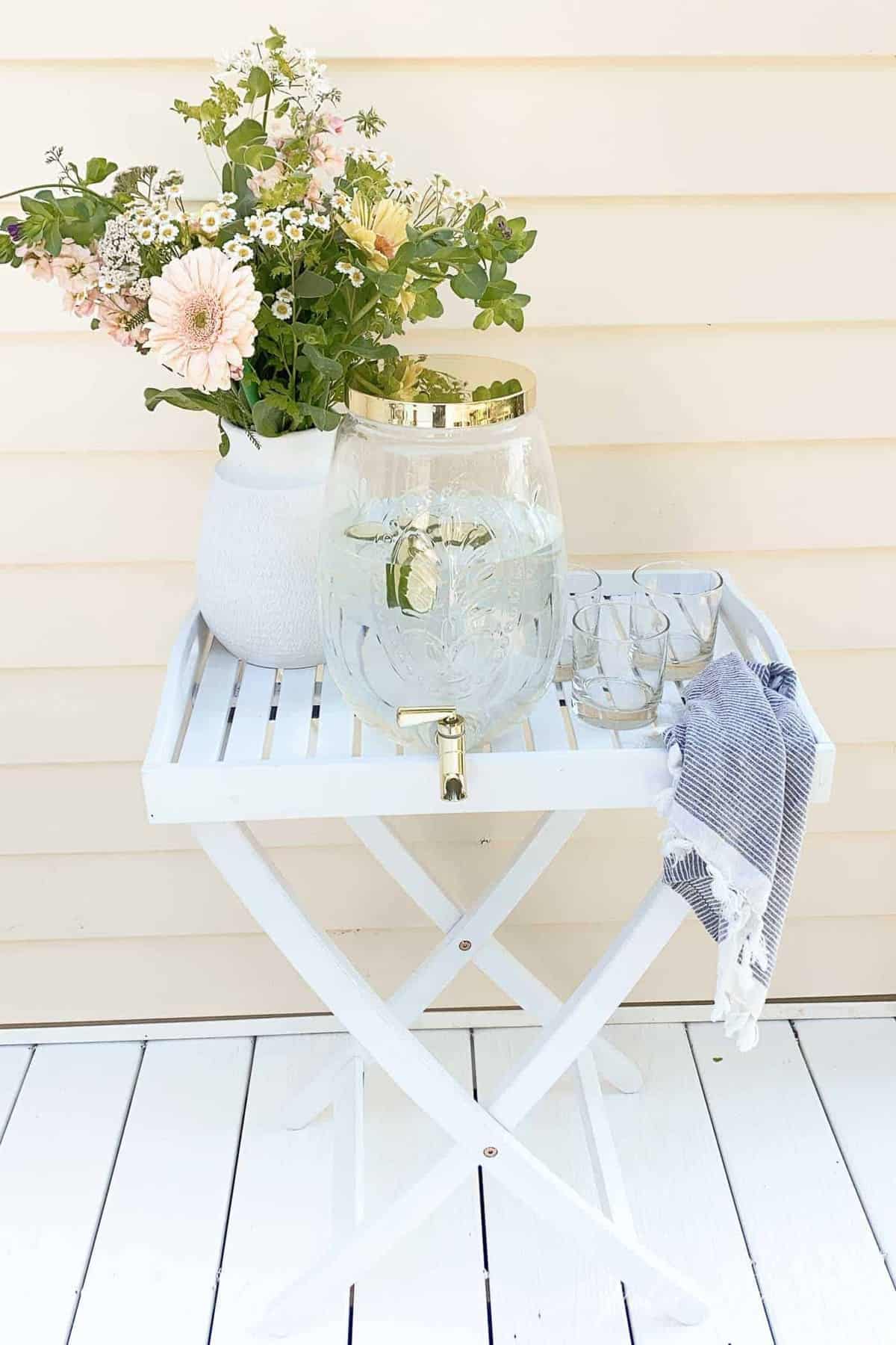 A white tray with flowers and water, on an exterior pvc deck.