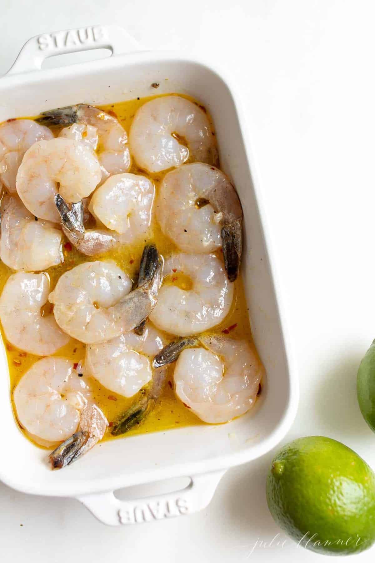 Pineapple shrimp marinade with large shrimp in a white dish.
