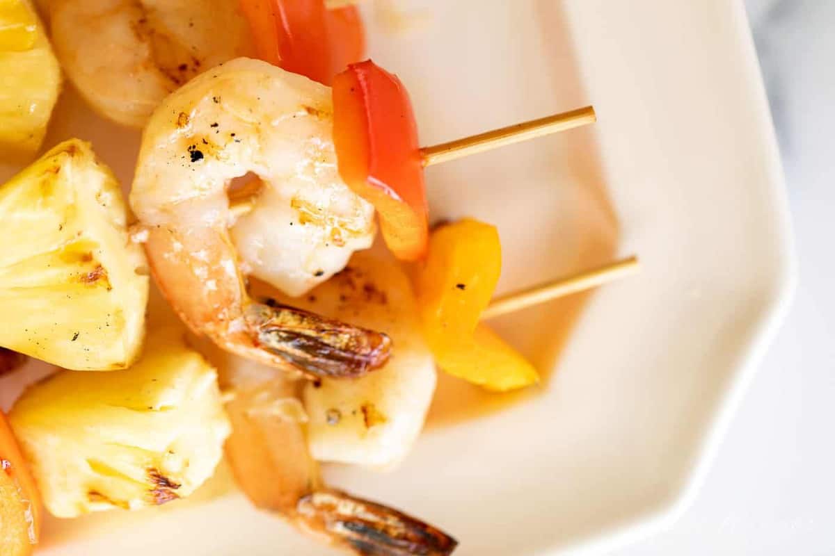 A white platter filled with pineapple shrimp skewers.