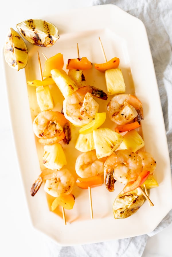 Pineapple shrimp skewers on a white plate.