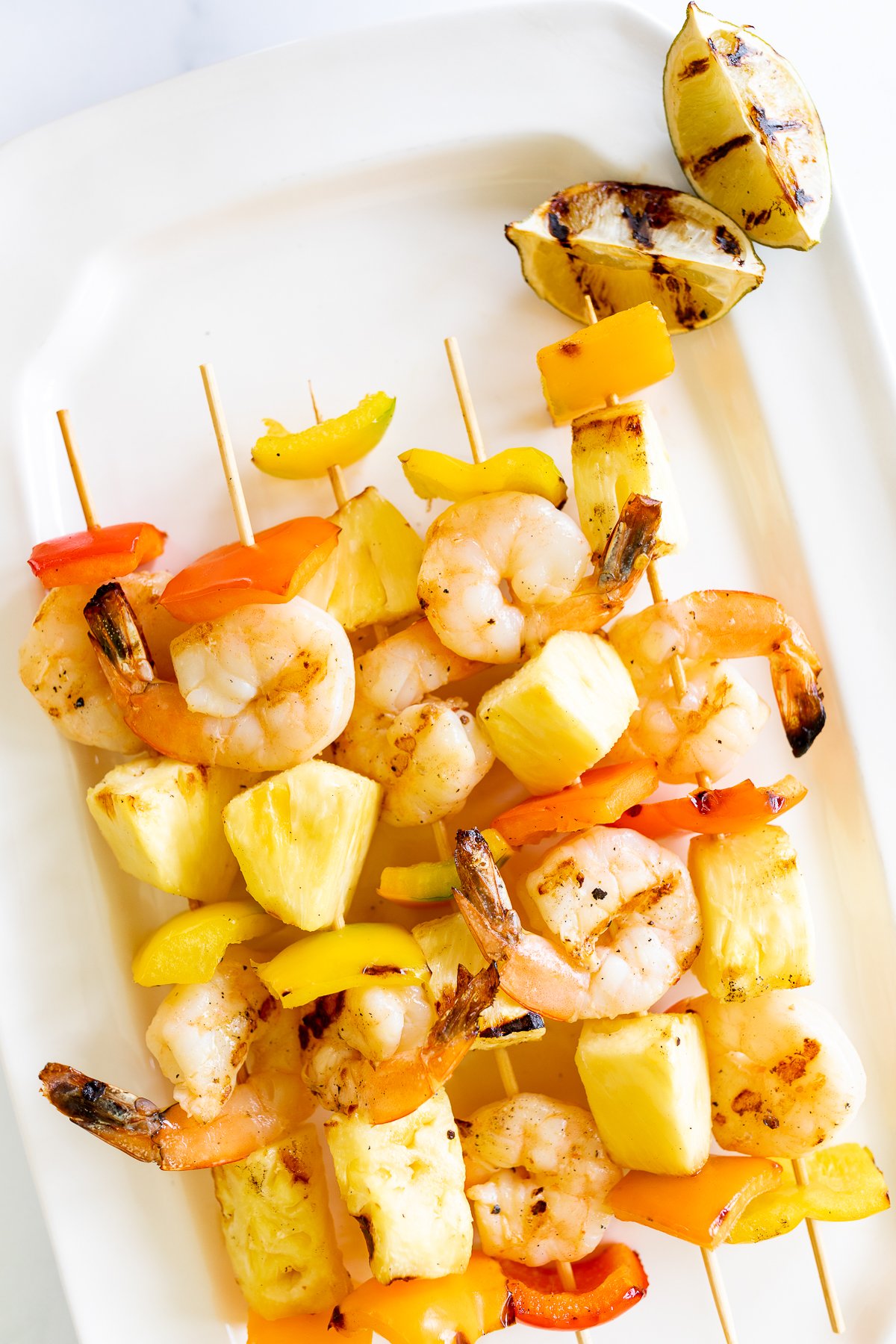 Pineapple shrimp skewers on a white plate.