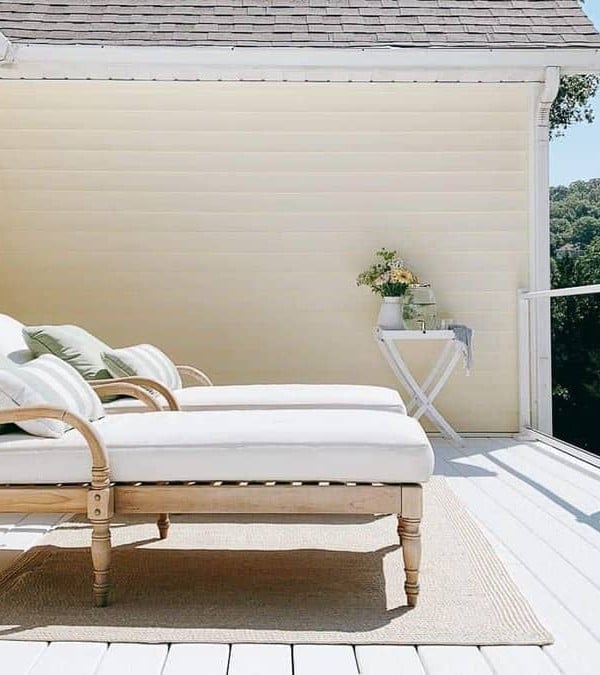 Two wooden lounge chairs placed on white vinyl decking at a lake house.