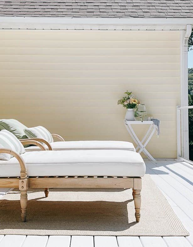 Two wooden lounge chairs placed on white vinyl decking at a lake house.
