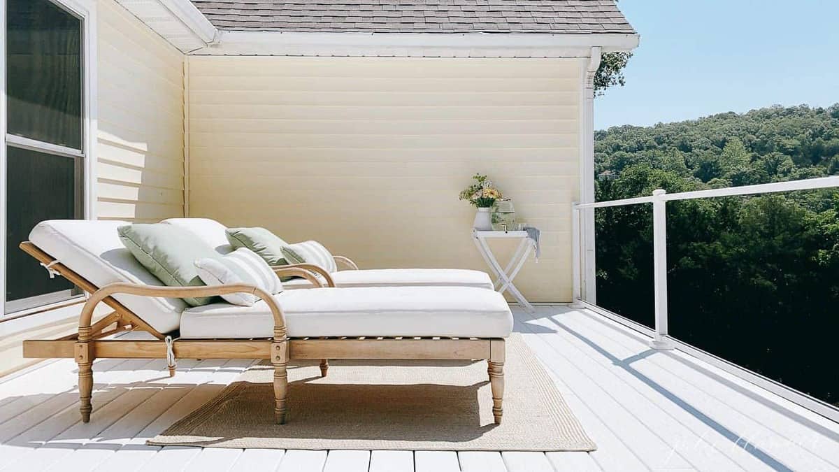 Two wooden lounge chairs placed on white vinyl decking at a lake house.