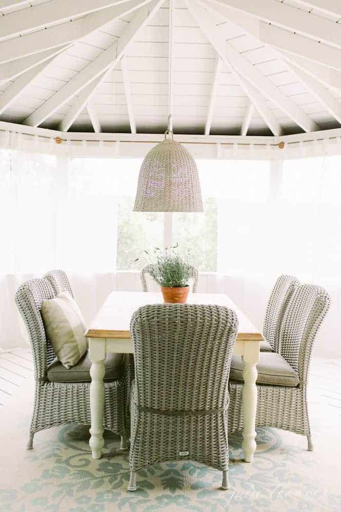 Wicker seating at a dining table on a screened in porch.