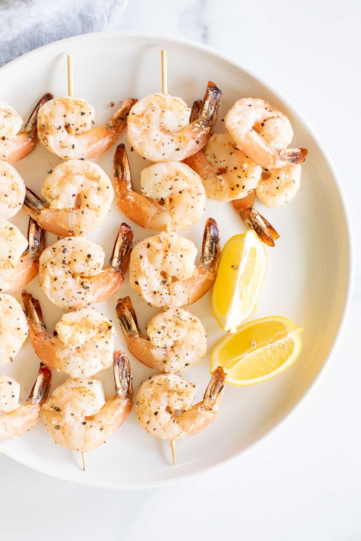 A white plate with lemon pepper shrimp kabobs