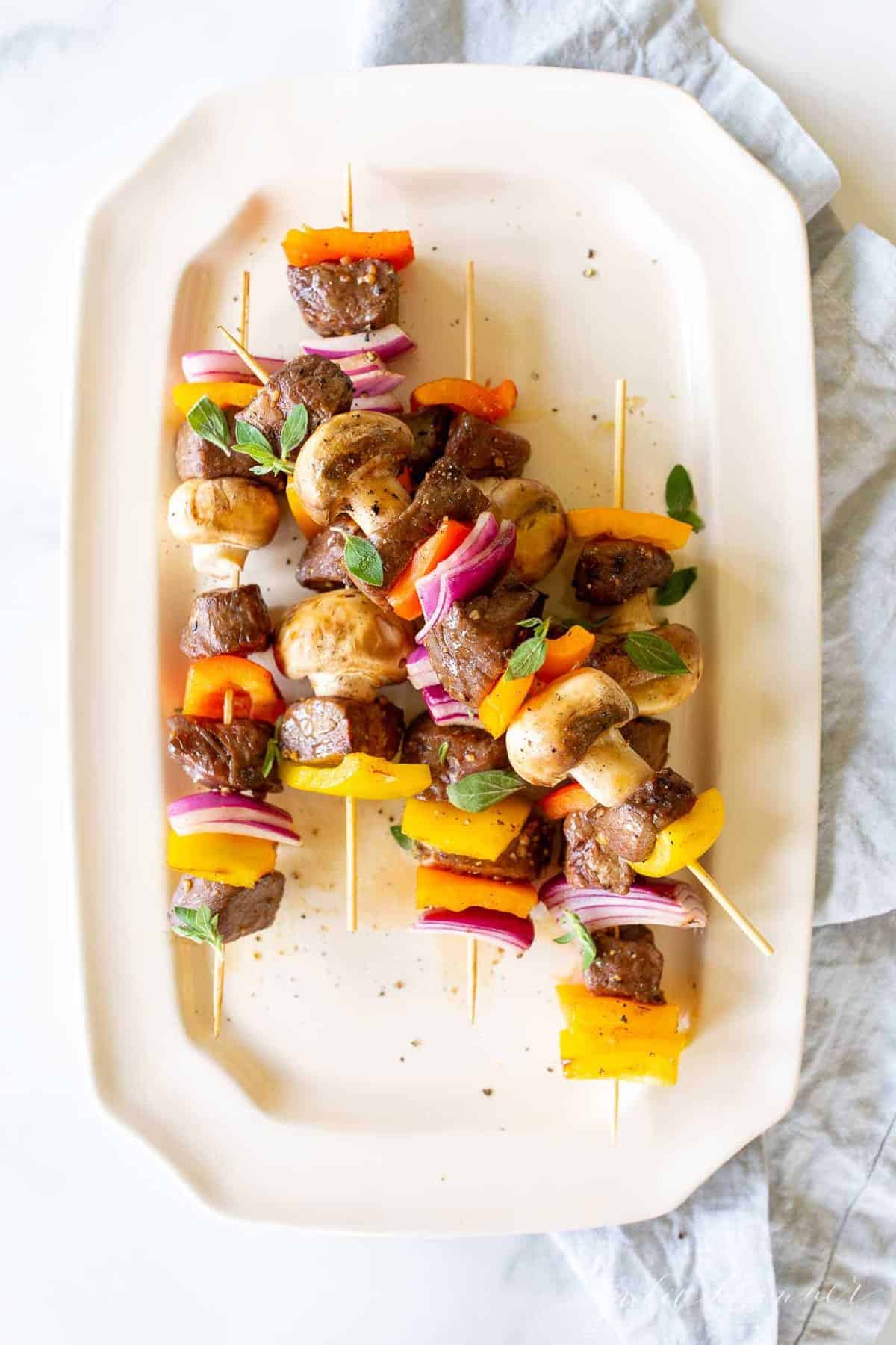 Grilled steak kabobs on a white platter. 