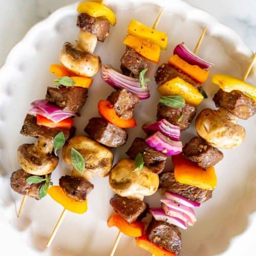 Grilled steak kabobs on a white platter.