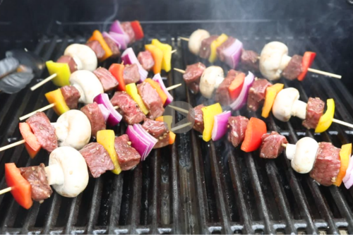 Steak kabobs with vegetables on a grill.