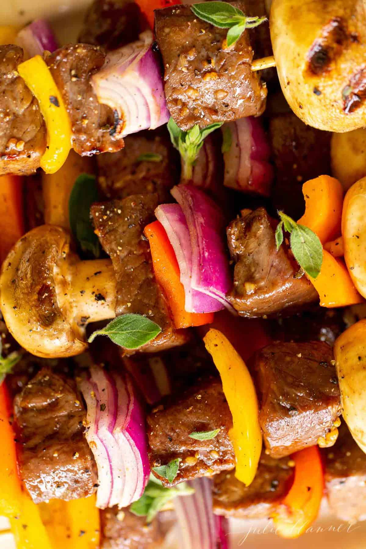 Grilled steak kabobs on a white platter. 