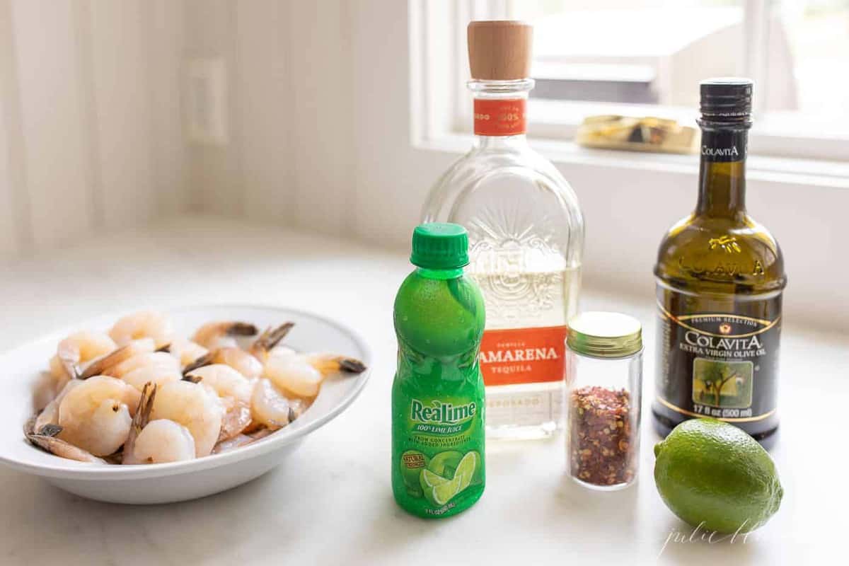 Ingredients for a tequila lime shrimp marinade with a platter of raw shrimp to the side.