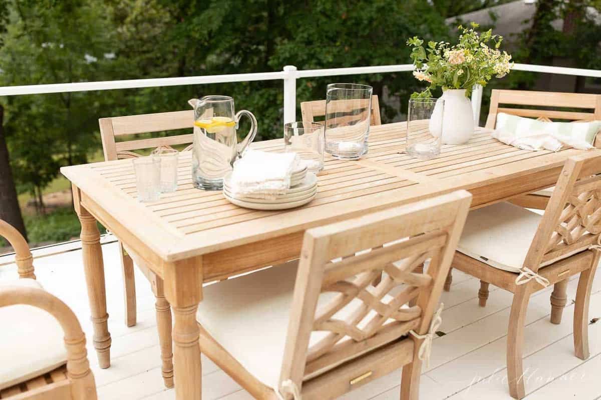 A teak dining set on a white vinyl deck.