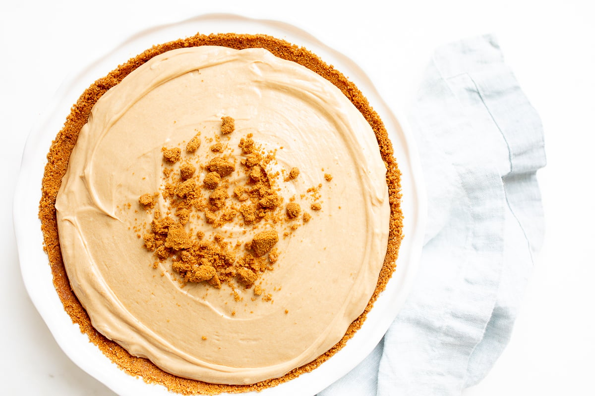 No bake cookie butter cheesecake in a white ceramic pie pan.