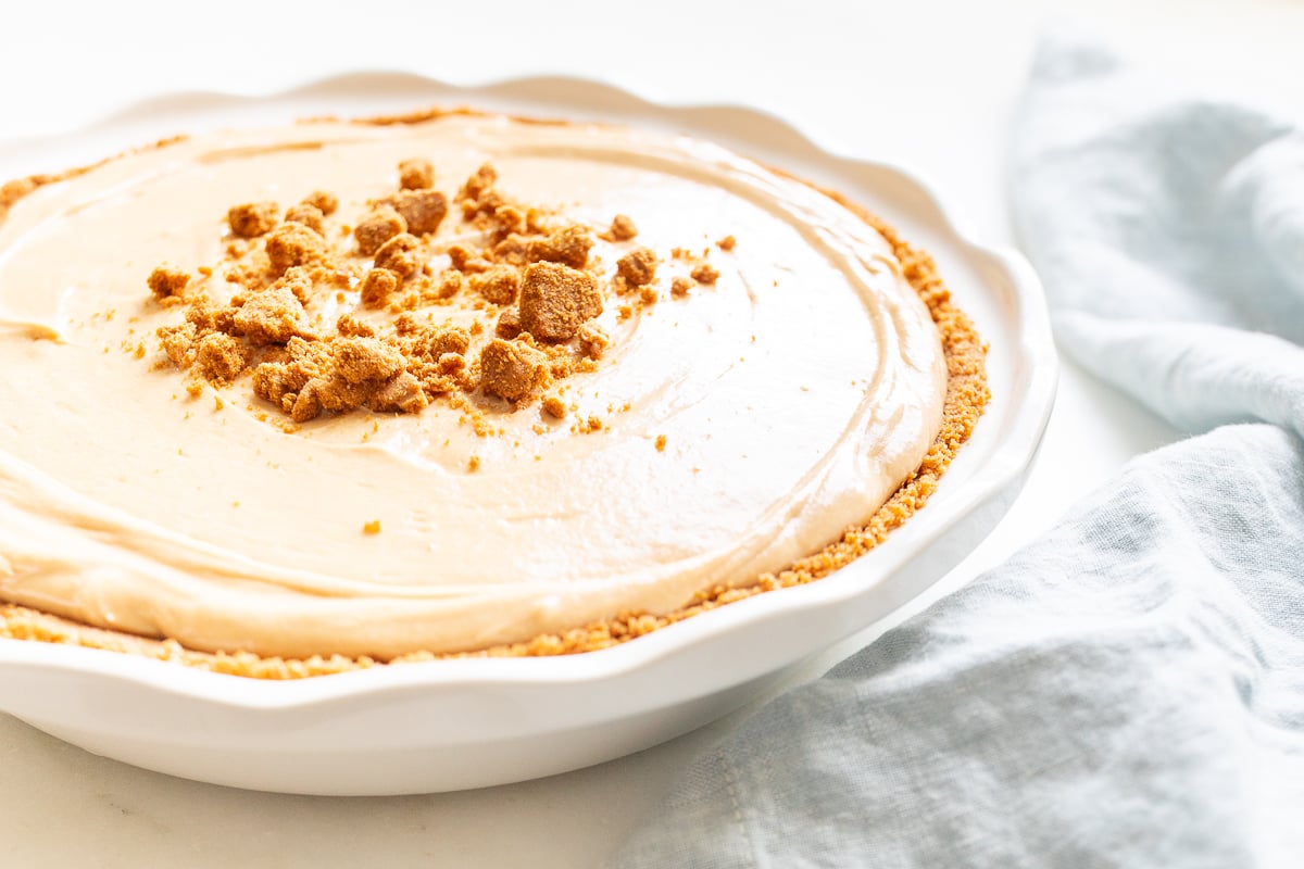 No bake cookie butter cheesecake in a white ceramic pie pan.