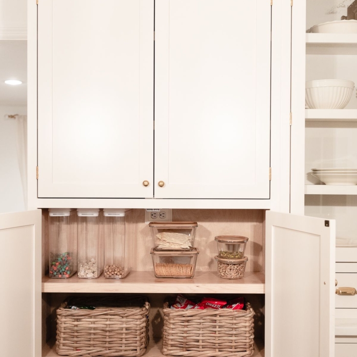 A kitchen pantry cabinet organized with baskets full of snacks for back to school organization