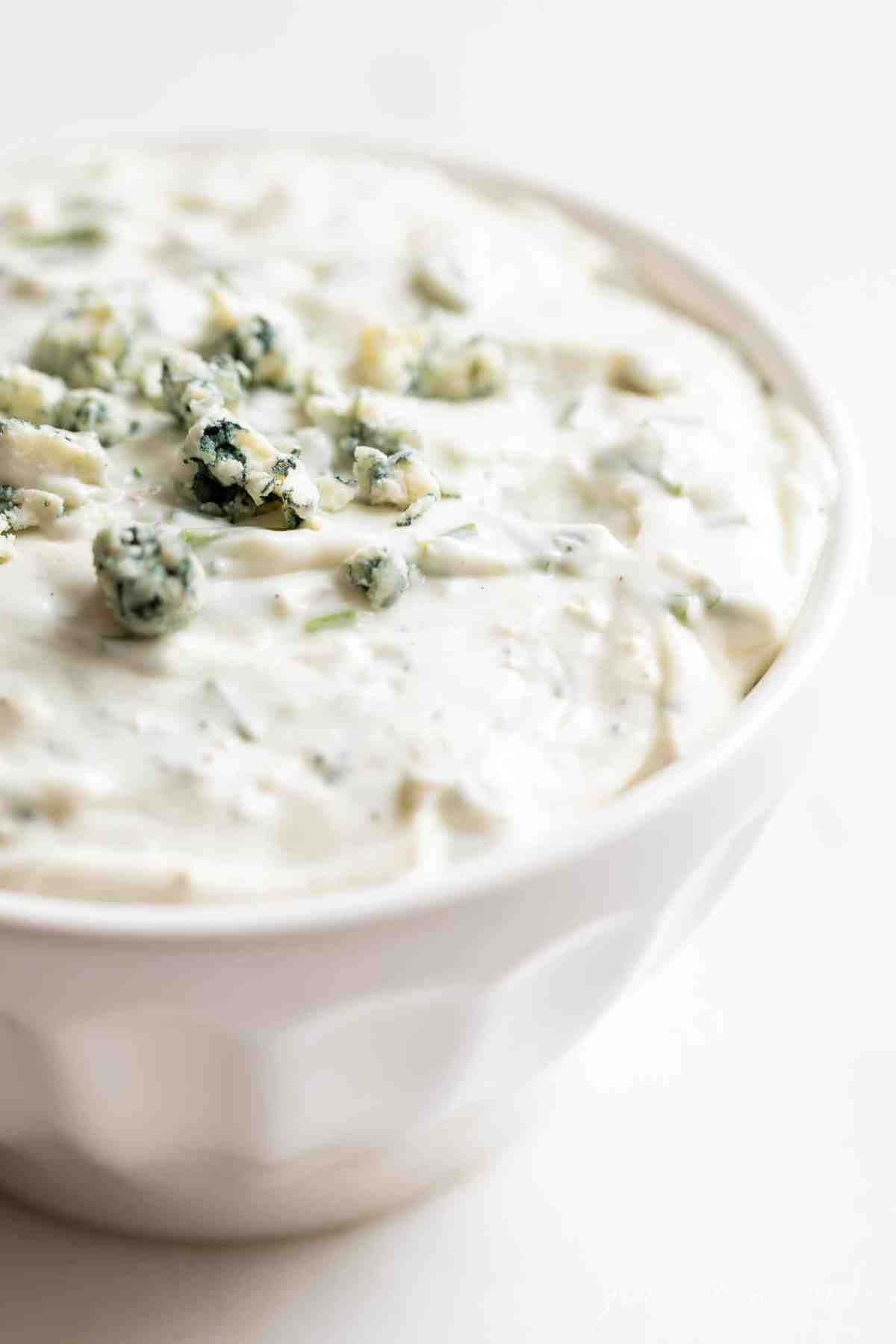 closeup of dip in white bowl with blue cheese on top