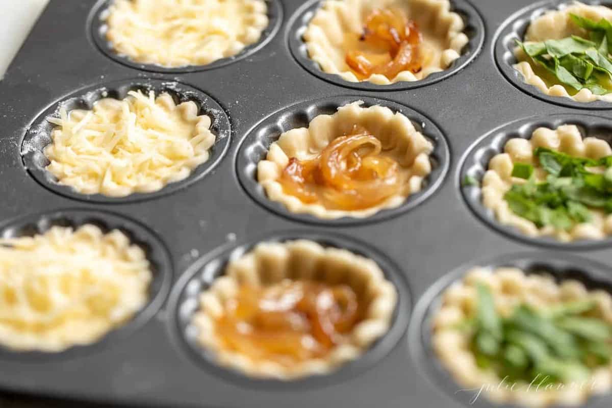 A muffin pan with cheddar cheese tart ingredients in each cup.