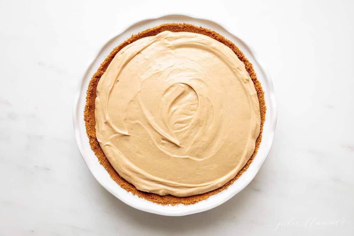 A white pie plate filled with a cookie butter cheesecake recipe.