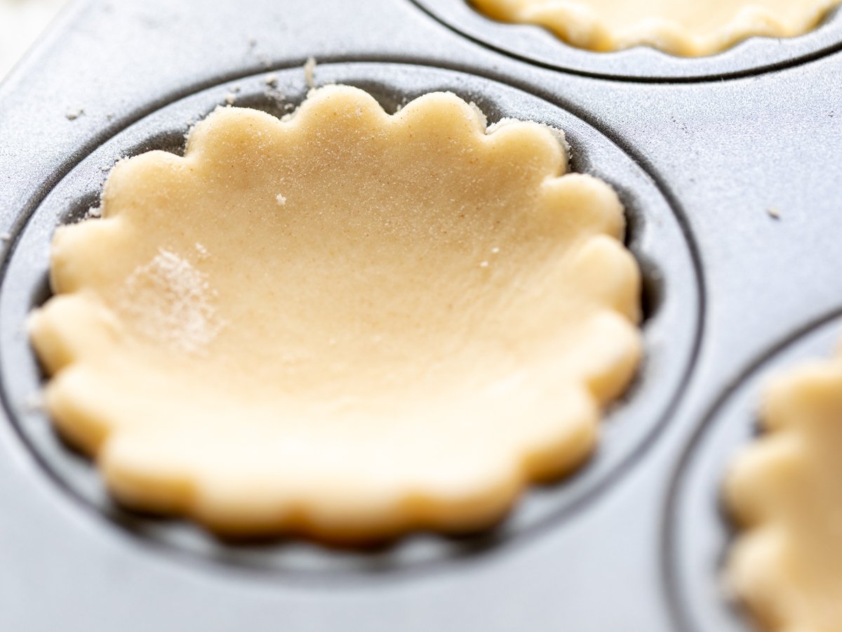 an unbaked cream cheese pie crust cut into a round shape for mini cheese tarts.