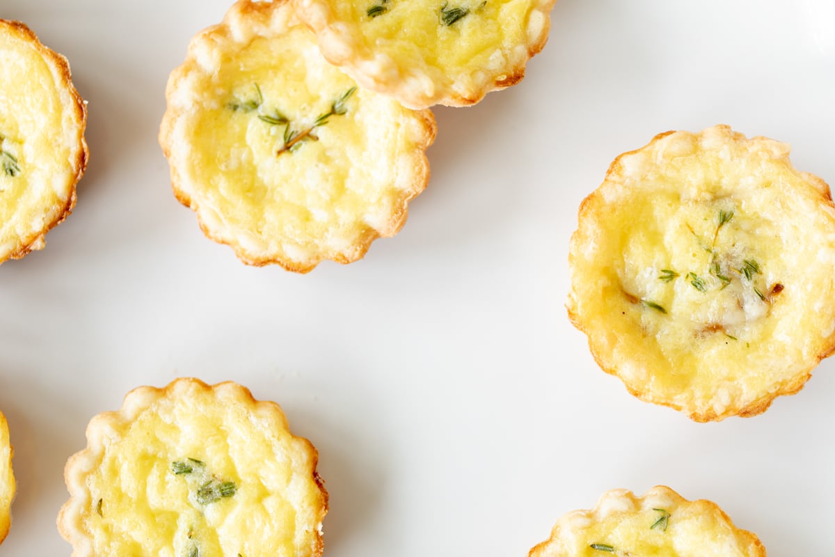 Mini cheese tarts with cream cheese pie crusts on a white surface.