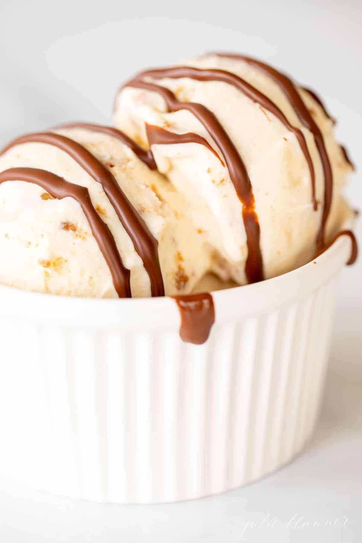 A white ramekin filled with vanilla ice cream and covered with dripping chocolate homemade magic shell.