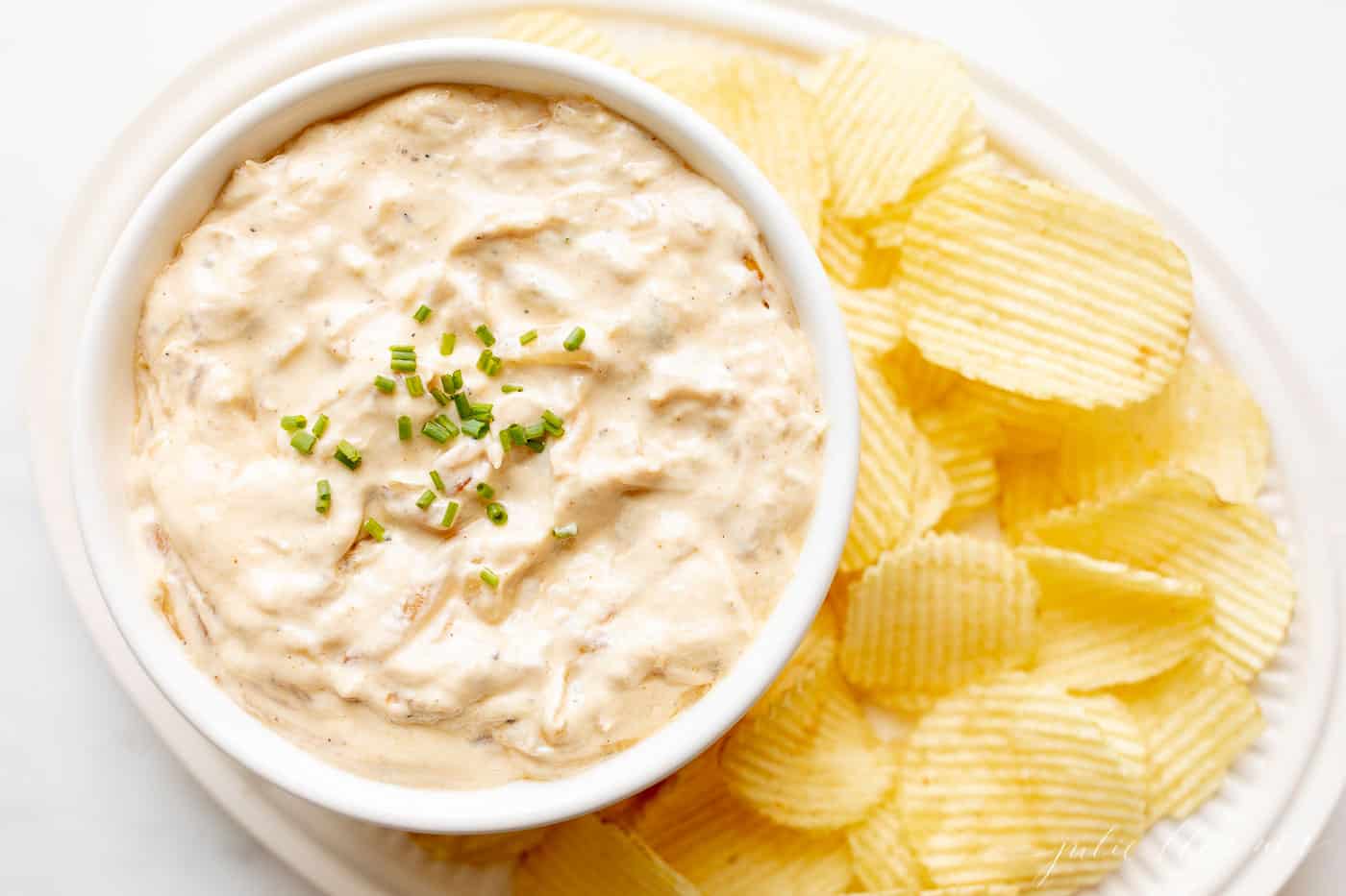 french onion dip in bowl with platter of ruffle chips