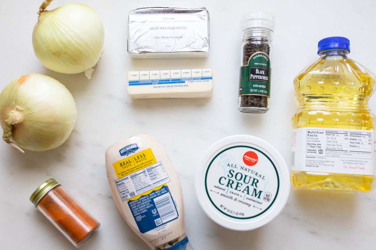 Ingredients for a French onion dip recipe laid out on a marble surface. 