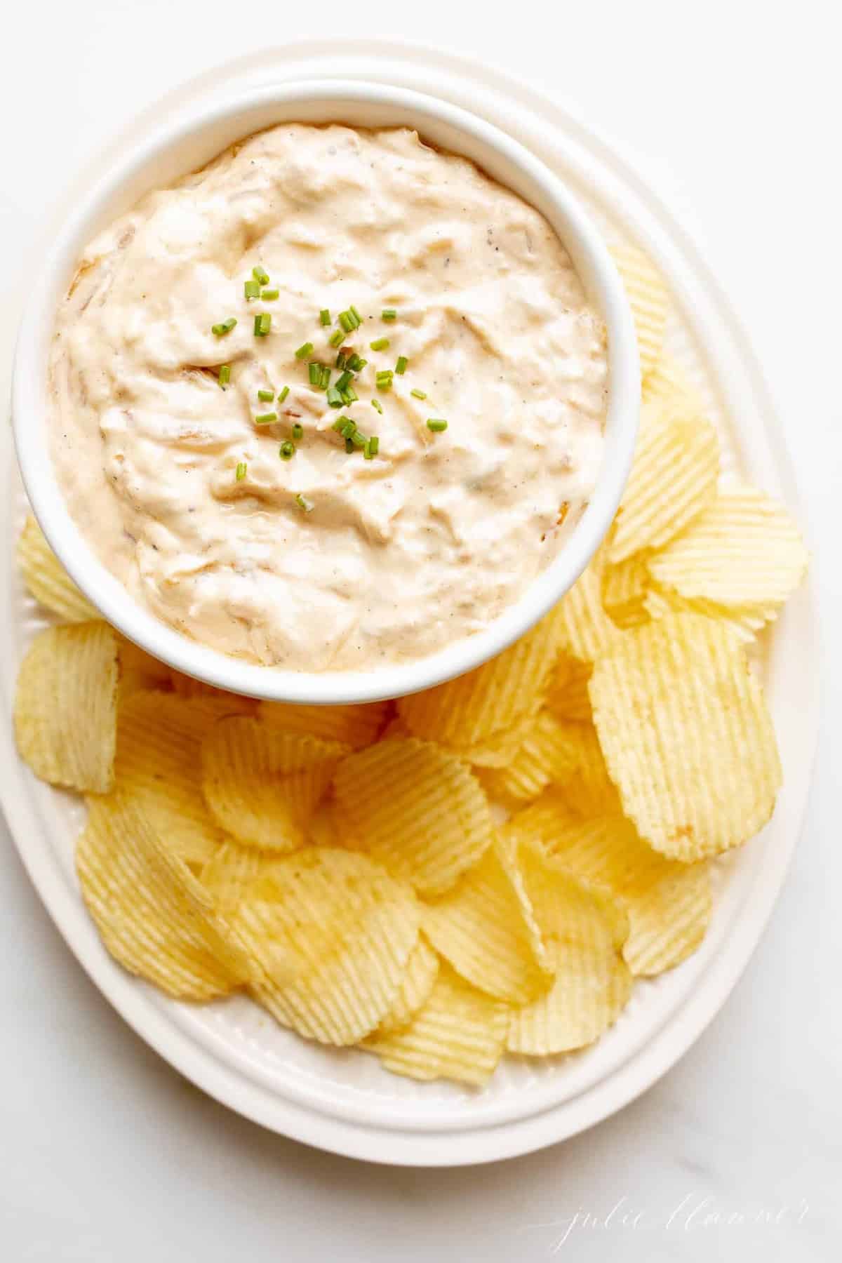french onion dip in bowl on platter with ruffle chips