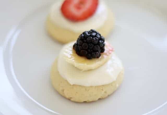 A white plate with sugar cookies with fruit pizza toppings