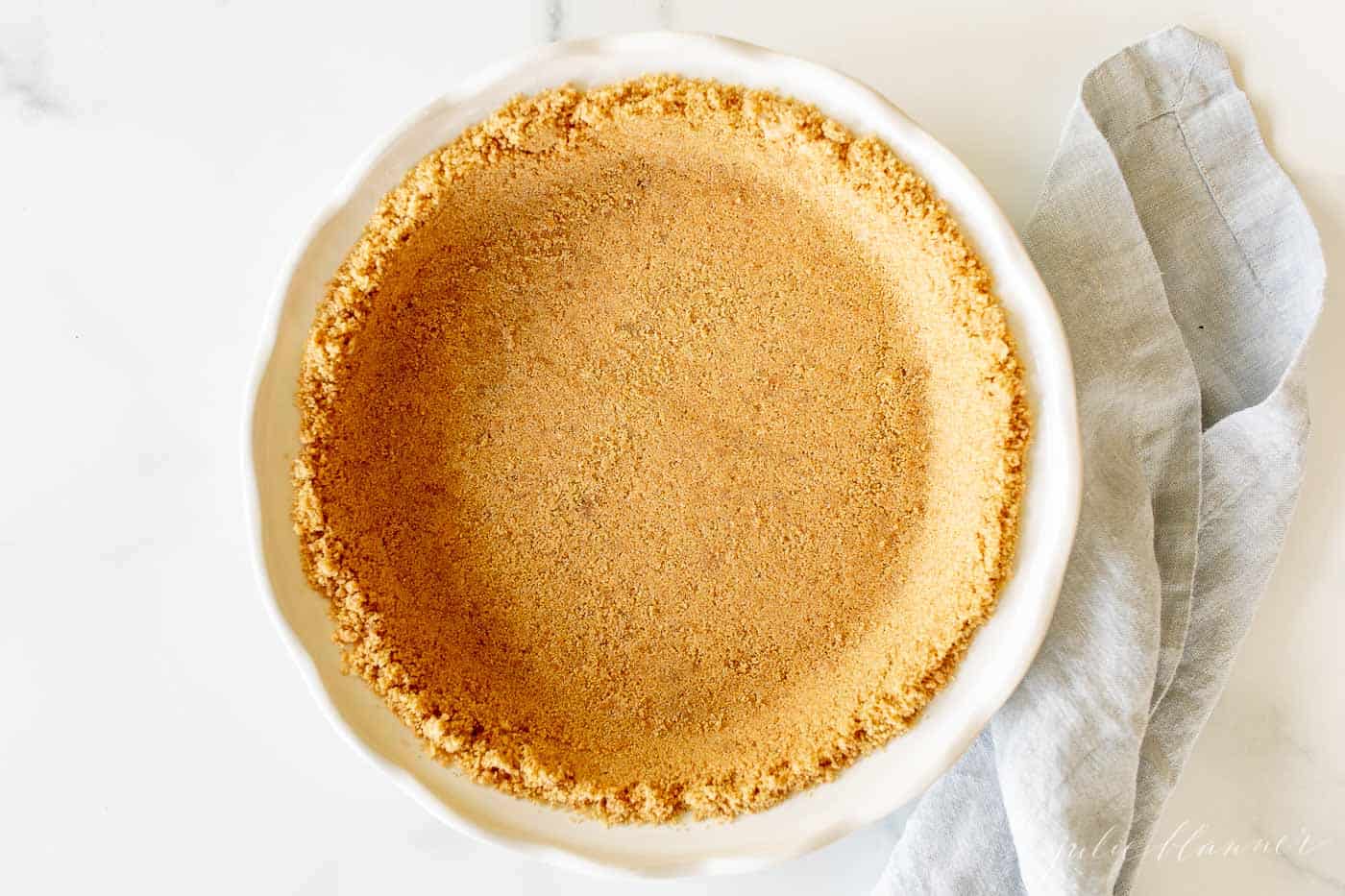 graham cracker pie crust in white dish with blue napkin