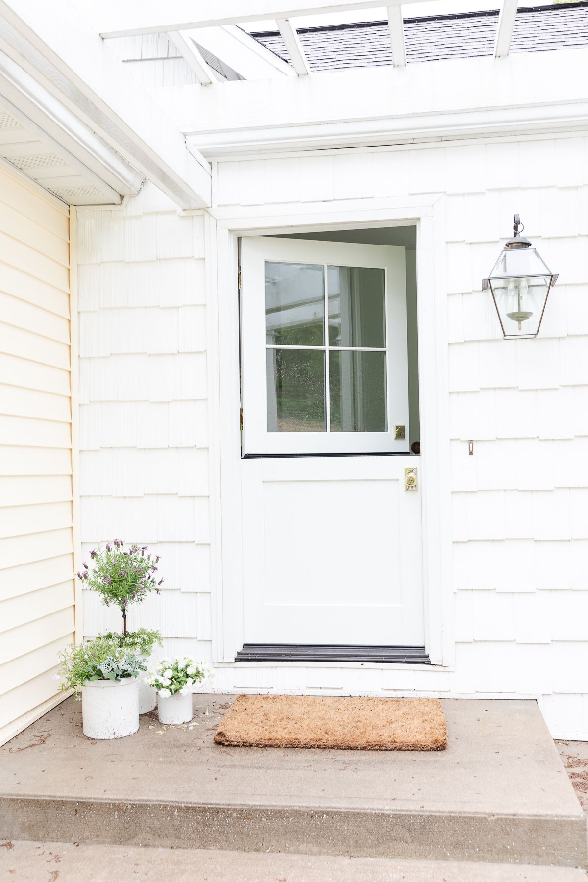 A white cottage home with a white dutch door, top half is open